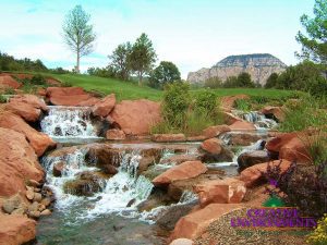Beautiful Sedona landscape on golf course with custom natural looking waterfall around red rocks with mountains in the background