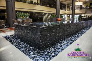Large Biltmore conference center with water feature centerpiece with stone siding and pebble base with custom hardscape