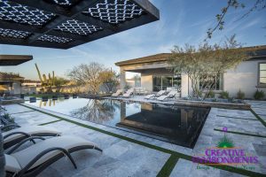 Custom backyard with zero edge pool, desert landscape, and lounge area