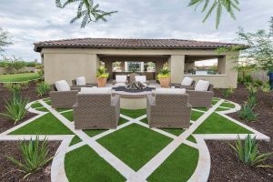 Custom landscaped backyard with a zero edge pool with a lounge area over uniquely patterned artificial grass with stamped concrete