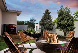 Custom backyard with large metal fire pit and wooden chairs with custom gardening area for vegetables