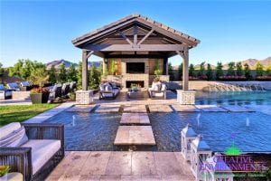 Custom outdoor landscape in Arizona backyard with floating steps in swimming pool to a covered patio with a fireplace