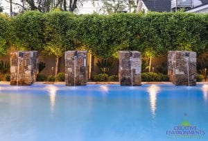 Custom outdoor landscape backyard swimming pool with stone water features with waterfalls