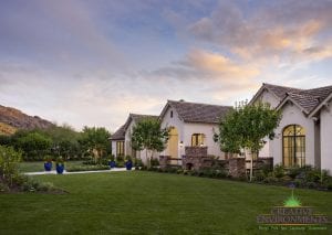 Custom outdoor landscape front yard with grass area and outdoor fireplace near large home