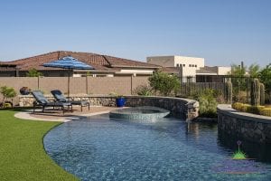 Custom outdoor landscape backyard swimming pool surrounding hot tub near seating area and stone edge under cactus