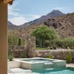 Custom backyard design with blue pool, raised spa and metal gate.