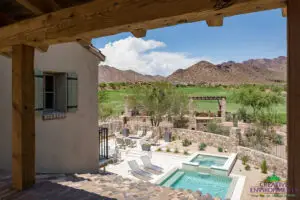 Custom backyard design with natural stone accents, multiple seating areas and blue pool and spa.