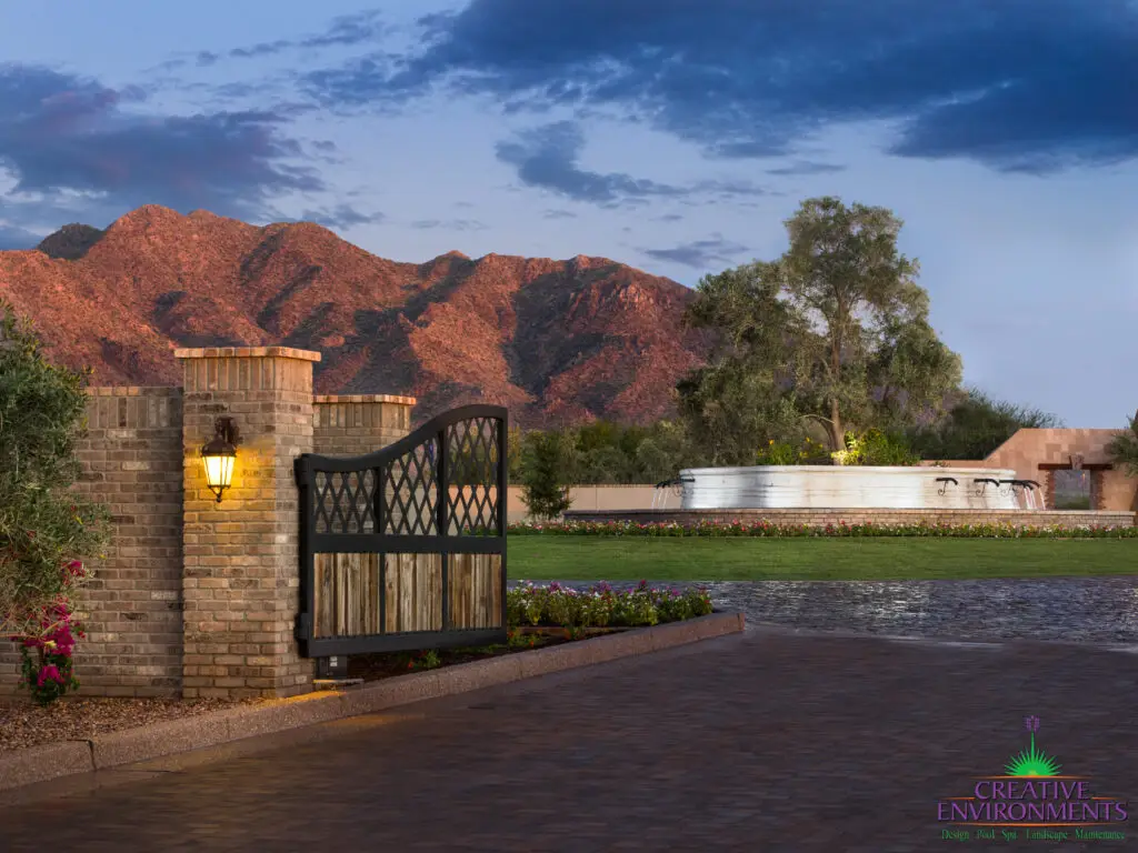 Custom community entrance with large water fountain, metal entry gate and roundabout driveway.