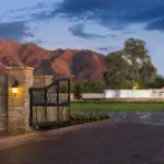 Custom community entrance with large water fountain, metal entry gate and roundabout driveway.