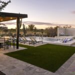 Custom backyard design with artificial turf, natural stone deck and multiple seating areas.