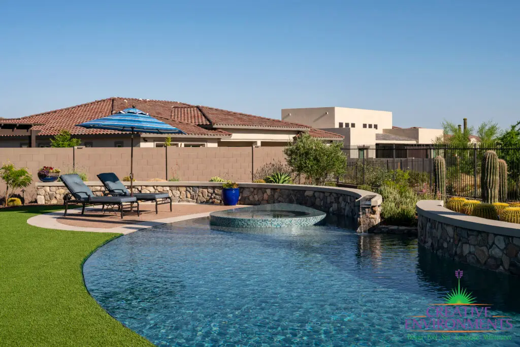 Custom backyard design with curved pool, raised spa and natural stone retention walls.