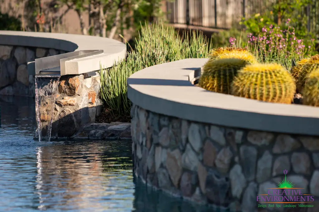 Custom backyard design with curved retention wall, curved pool and water feature into pool.