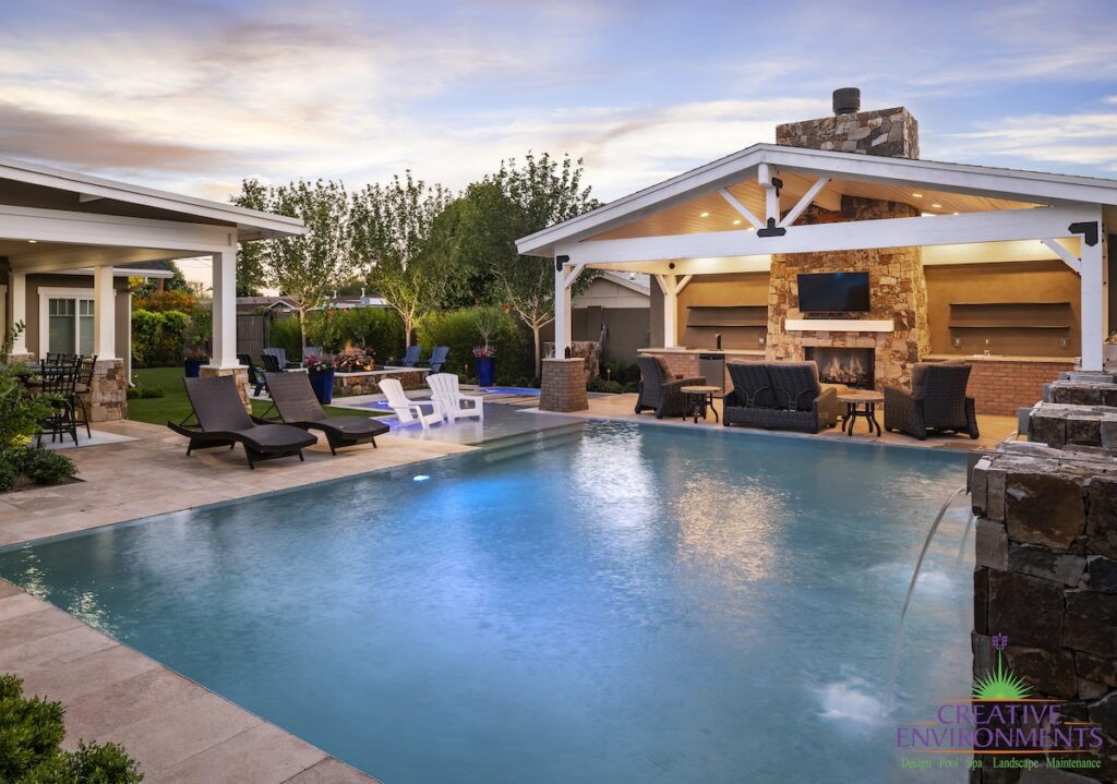 Custom backyard design with zero-edge pool, farmhouse shade structure and water columns.