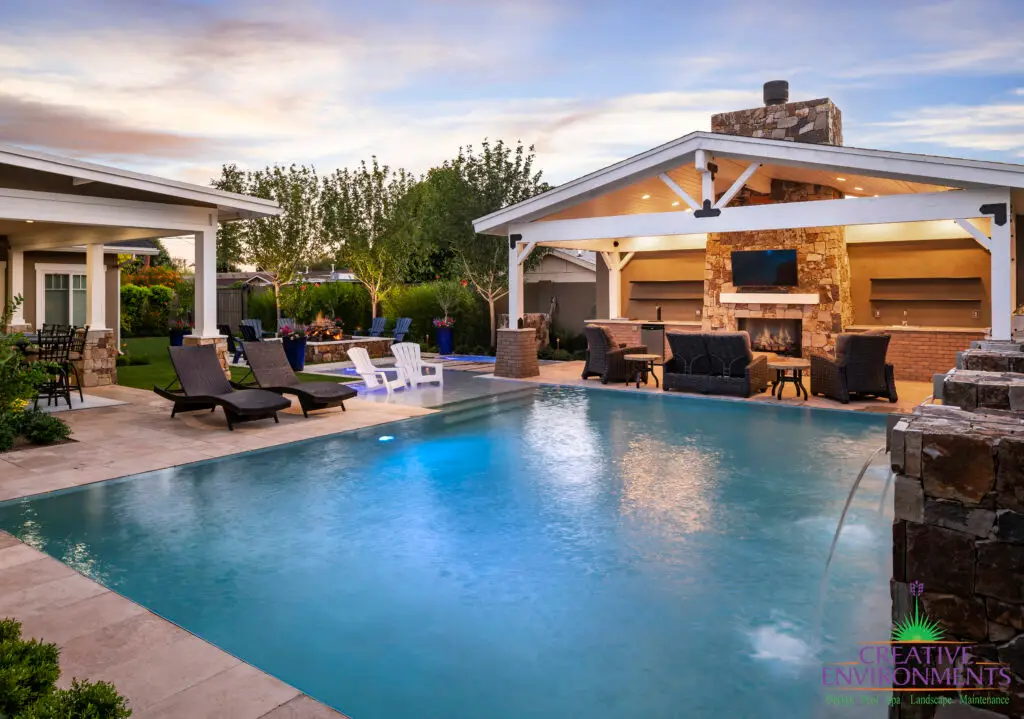 Custom backyard design with blue pool, farmhouse shade structure and multiple seating areas.