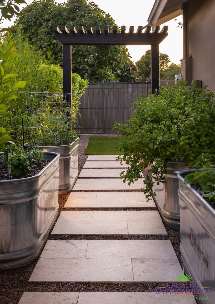 Custom backyard design with trellis archway, galvanized planters and natural stone steps.