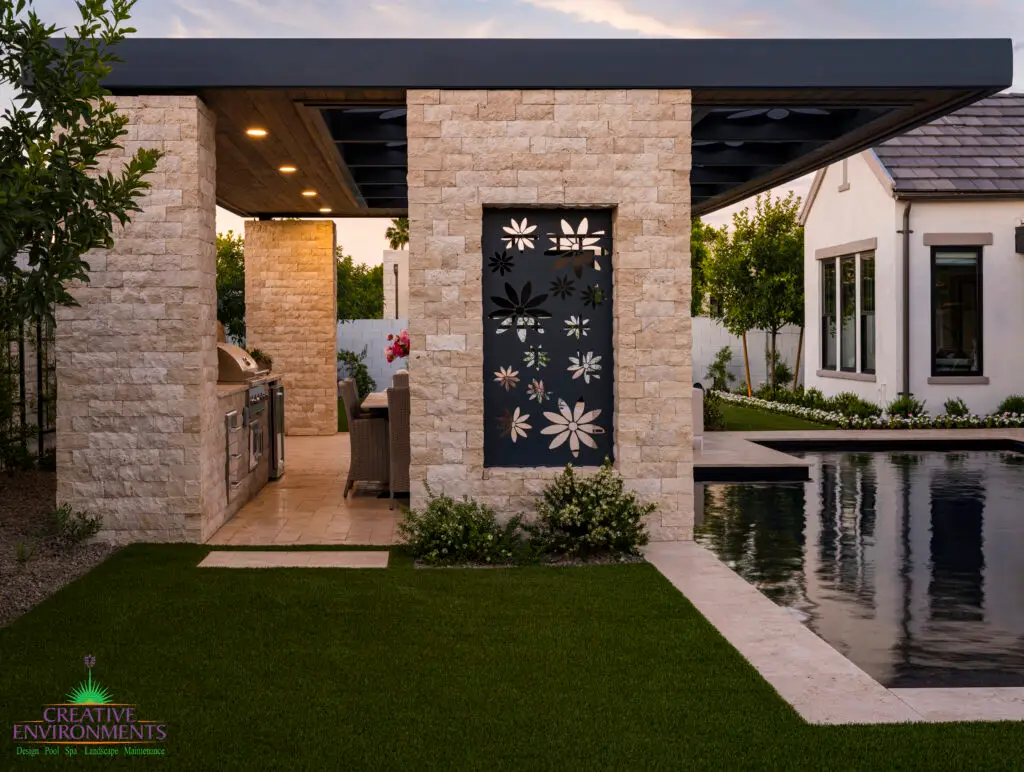 Custom backyard design with floral metal cutouts, black pool and artificial turf.