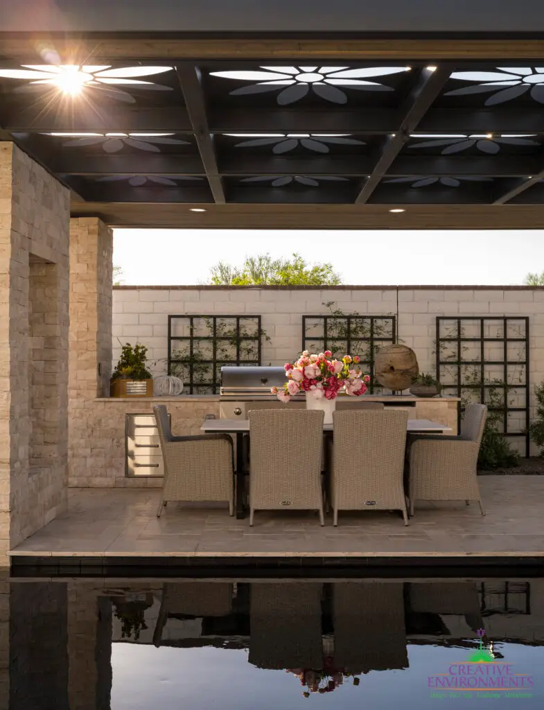 Custom metal shade structure with floral cutouts and natural stone columns.