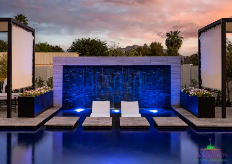 Custom backyard design with cabanas, Jesus steps and baja steps in front of water wall with blue water wall lighting.
