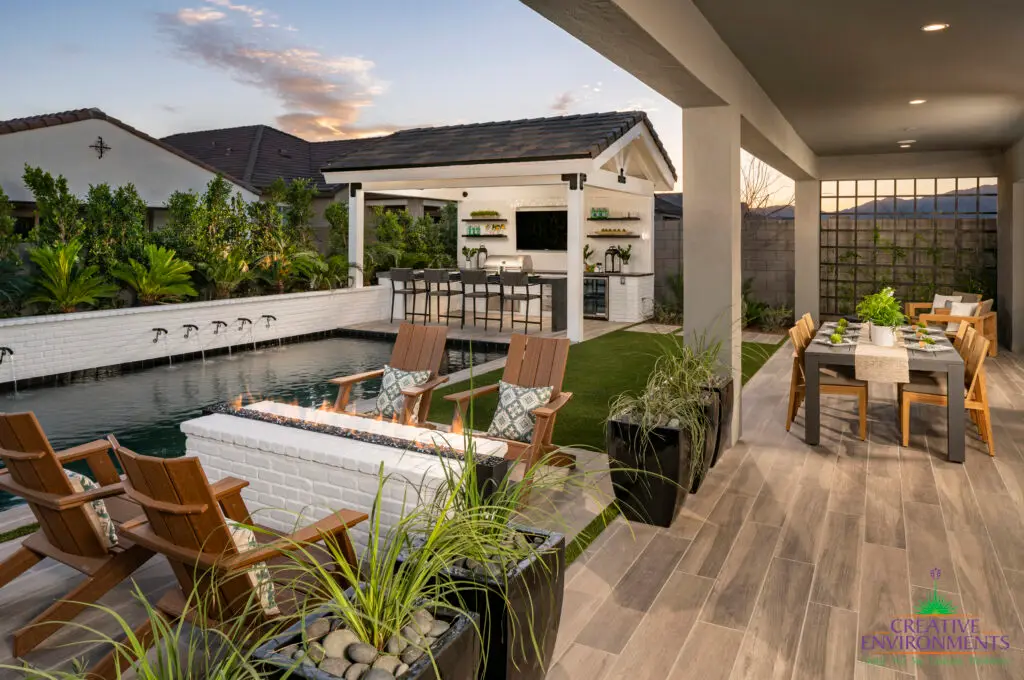 Custom backyard design with multiple seating areas, trellis and water feature into pool.