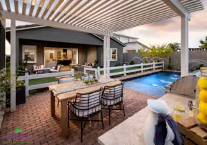 Custom backyard design with white metal shade structure, outdoor dining area and artificial turf.