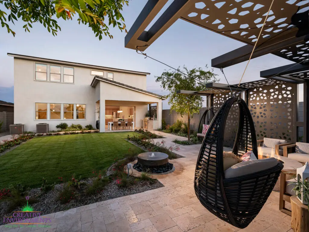Custom backyard design with hanging swing, water feature and real grass.