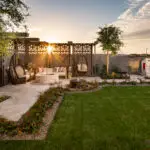 Custom backyard design with real grass, cantilevered shade structure with hanging swings and up lighting.
