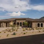 Custom front yard design with desert landscaping, natural stone paver driveway and cacti.
