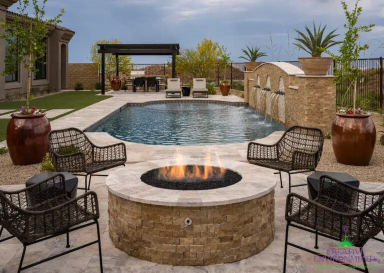 Custom backyard design with circular fire pit, slatted metal shade structure and water feature into pool.