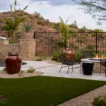 Custom backyard design with artificial turf, organized planting and large planters.