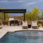 Custom backyard design with deco-tile pool, metal fencing and shade structure.