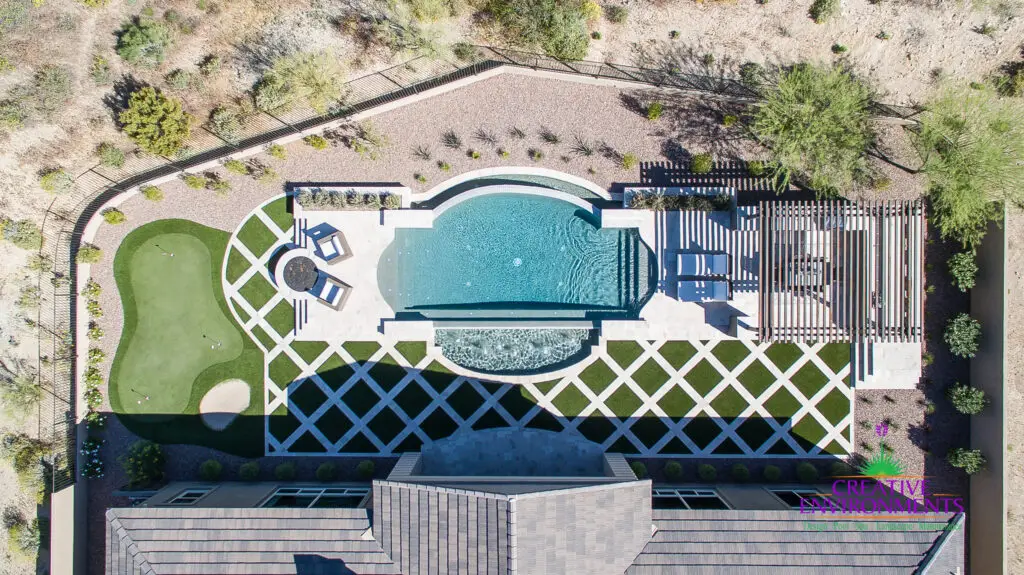 Custom backyard aerial view with unique shaped pool, putting green and artificial turf pattern.