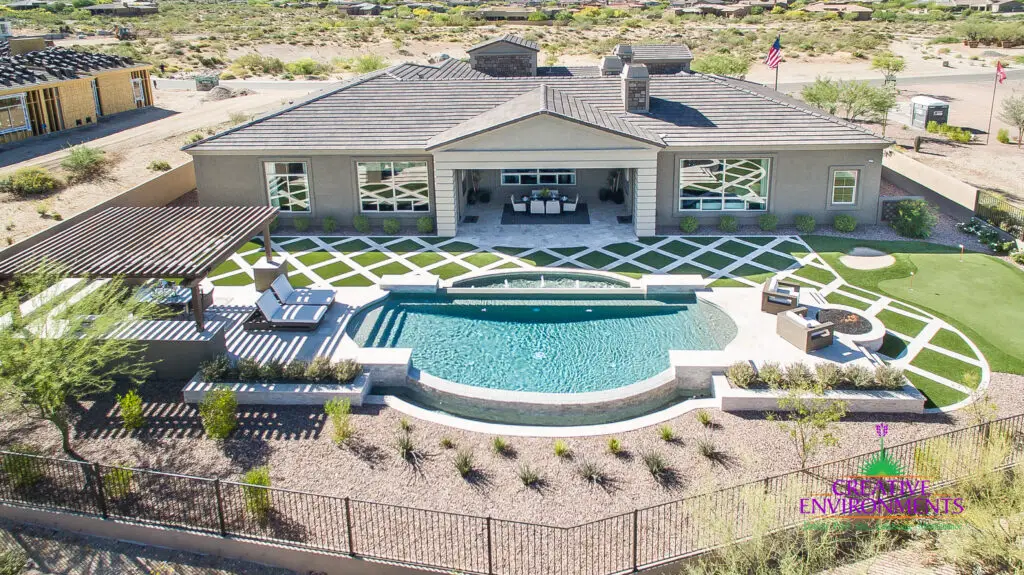Custom backyard design with artificial turf pattern, unique shaped pool and slatted shade structure.