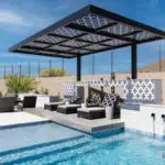Custom backyard design with cantilevered shade structure, metal scupper water feature into pool and large baja step.