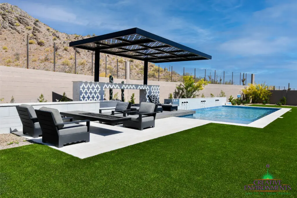 Custom backyard design with cantilevered shade structure, multiple seating areas and blue pool.