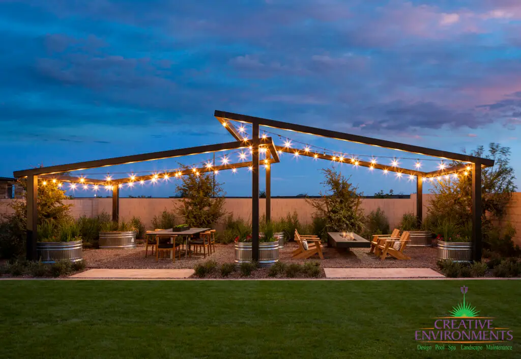 Backyard design with anged metal feature and string lights.