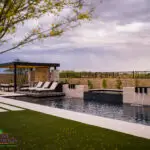 Custom backyard design with metal shade structure, raised black spa and pool.