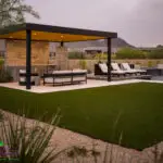 Custom backyard design with metal shade structure, artificial turf and multiple seating areas.