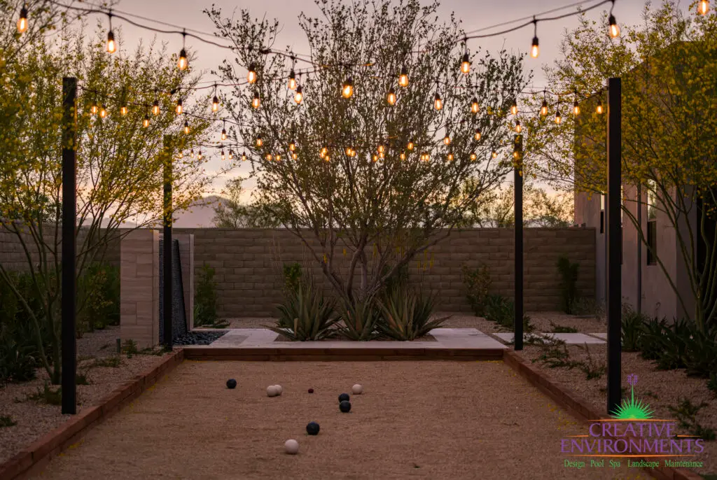 Custom backyard design with black water wall, bocce ball court and string lights.