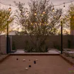Custom backyard design with black water wall, bocce ball court and string lights.
