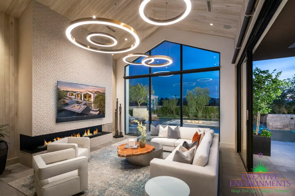Custom indoor/outdoor living experience with up lighting, sunken fire pit into pool and trees.
