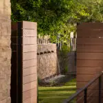 Custom side yard design with wooden door, water feature and metal fencing.