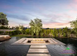 Custom backyard design with sunken fire pit into pool, Jesus steps and privacy hedges.