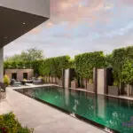 Custom backyard design with black pool, water columns and privacy hedges.