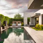 Custom backyard design with multiple seating areas, water columns and black pool.
