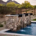 Custom metal scupper water feature into pool with desert landscape design.
