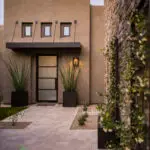 Custom front yard design with large metal planters, metal trellis and natural stone pathway.