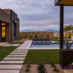Custom backyard design with artificial turf, blue pool and raised spa.