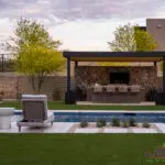 Custom backyard design with metal shade structure, outdoor dining area and pool.