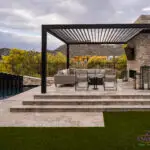 Custom backyard design with slatted shade structure, raised outdoor seating area and artificial turf.