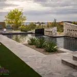 Custom backyard design with metal fencing, natural stone decking and raised outdoor entertainment area.